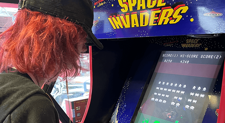 Alex playing on a space invaders arcade machine.