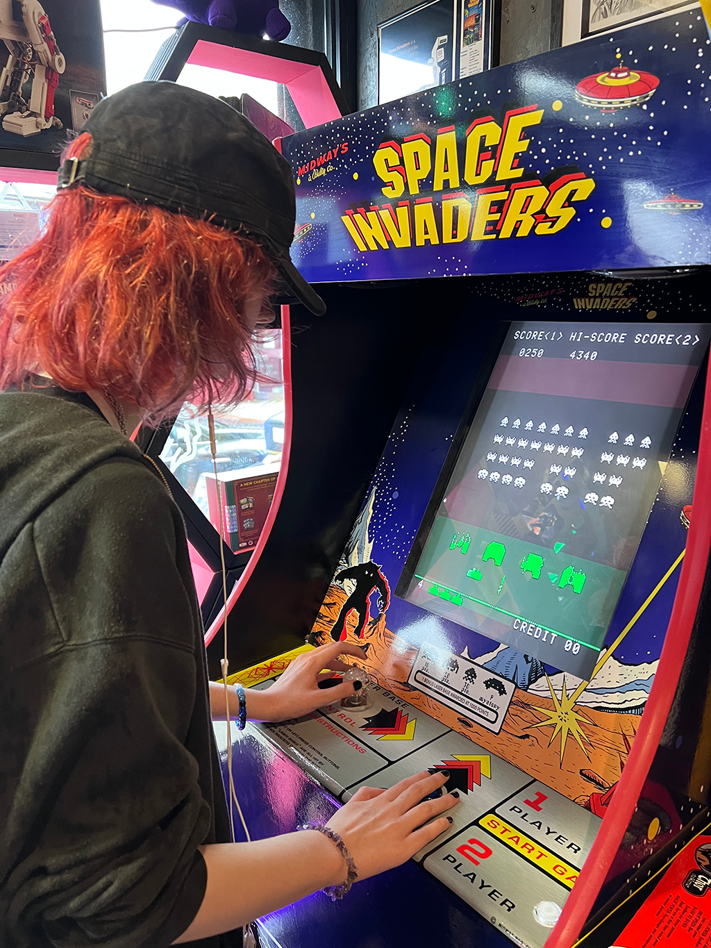 Alex playing on a space invaders arcade machine.