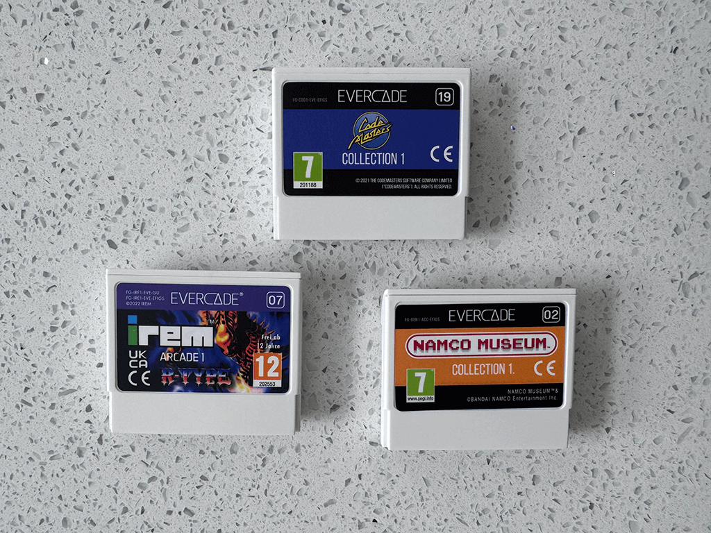 Three Evercade video game cartridges on a gray speckled surface: Jaleco Collection 1, IREM Arcade 1, and Namco Museum Collection 1.