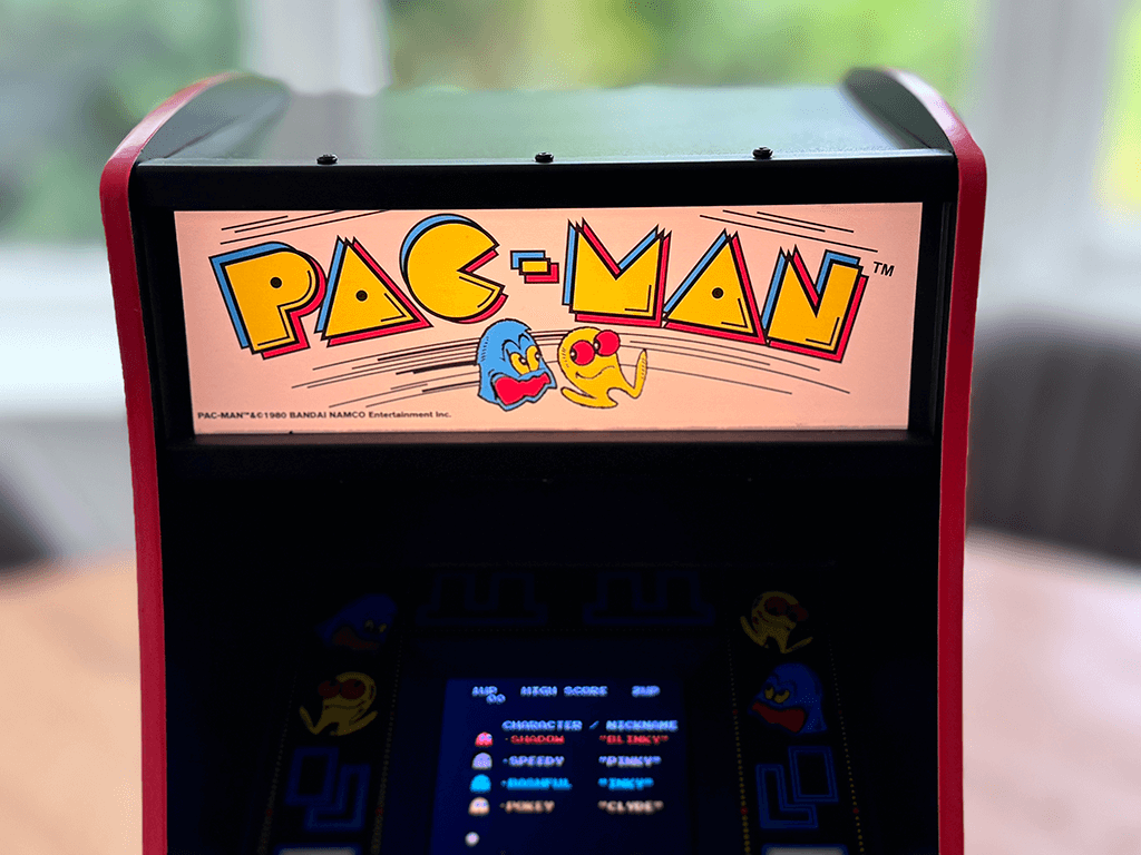 A PAC-MAN Quarter Arcade close up showing a lit Marquee and game playing.