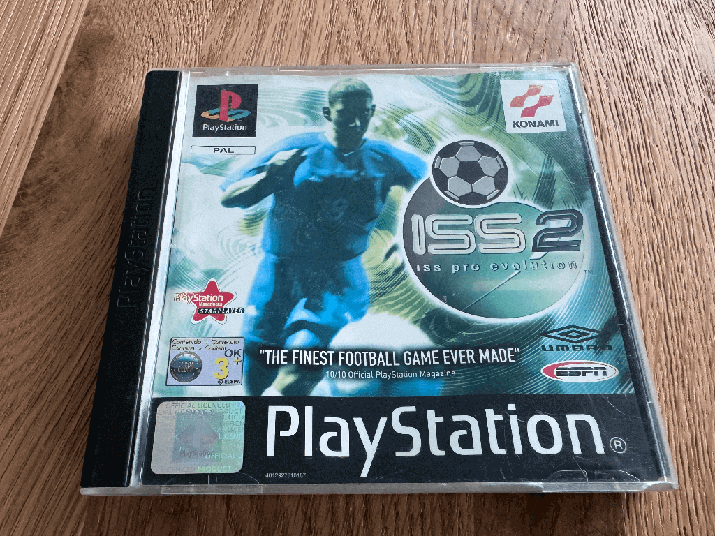 A copy of the Playstation 1 Pro Evolution Soccer 2 game in a case in a wooden table top.