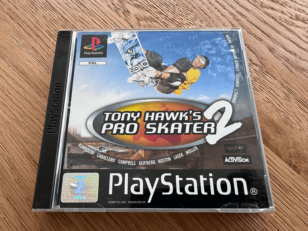 A copy of the Playstation 1 Tony Hawks Pro Skater 2 game in a case in a wooden table top.