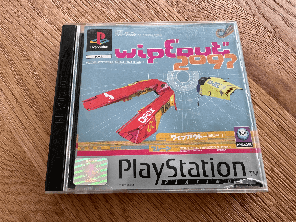 A copy of the Playstation 1 Wipeout 2097 game in a case in a wooden table top.