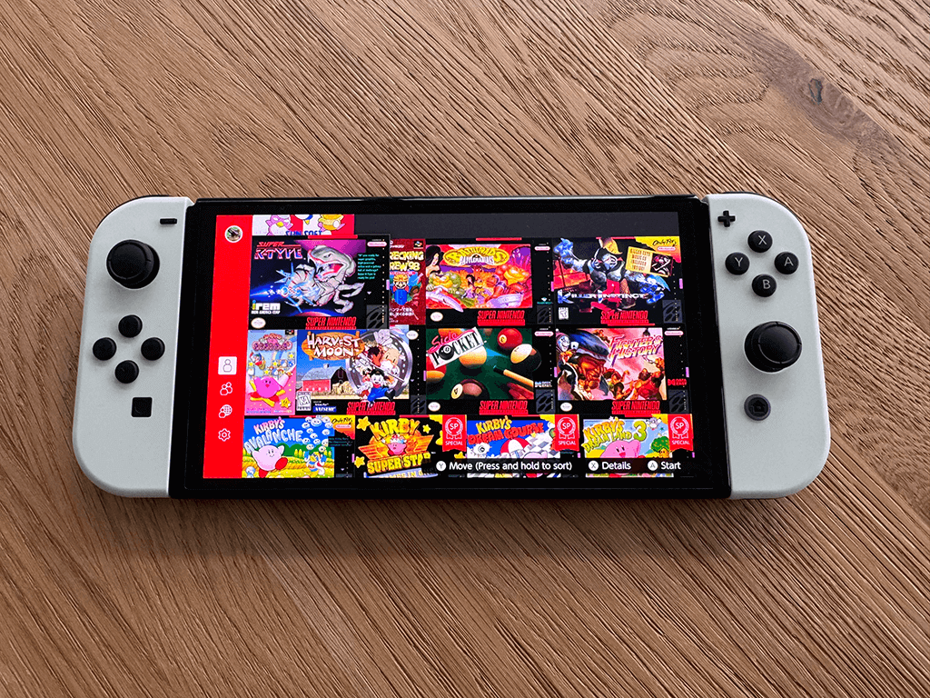 A Nitendo OLED Switch on a wooden surface displaying a selction of games from Nintendo Switch Online.