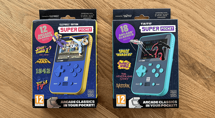 The Taito and Capcom Super Pockets in packaging on a wooden table top.