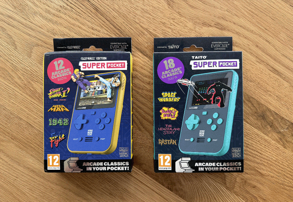 The Taito and Capcom Super Pockets in packaging on a wooden table top.