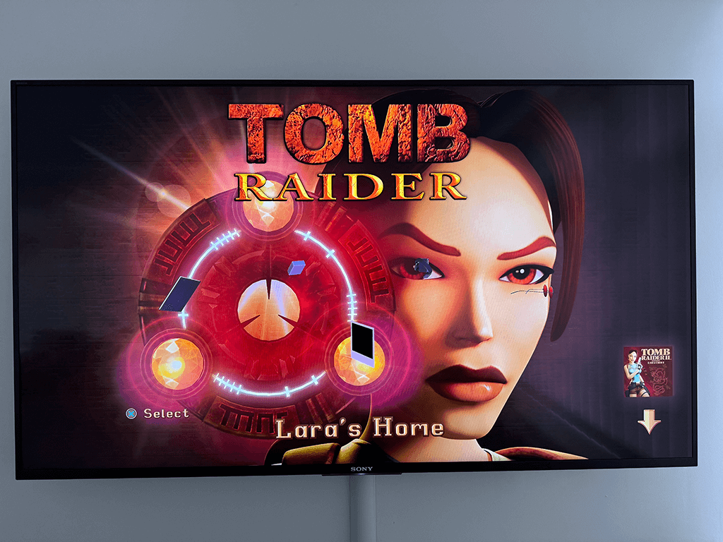 A Sony TV on a wall disaplaying the Tombraider 1-3 Remastered game.